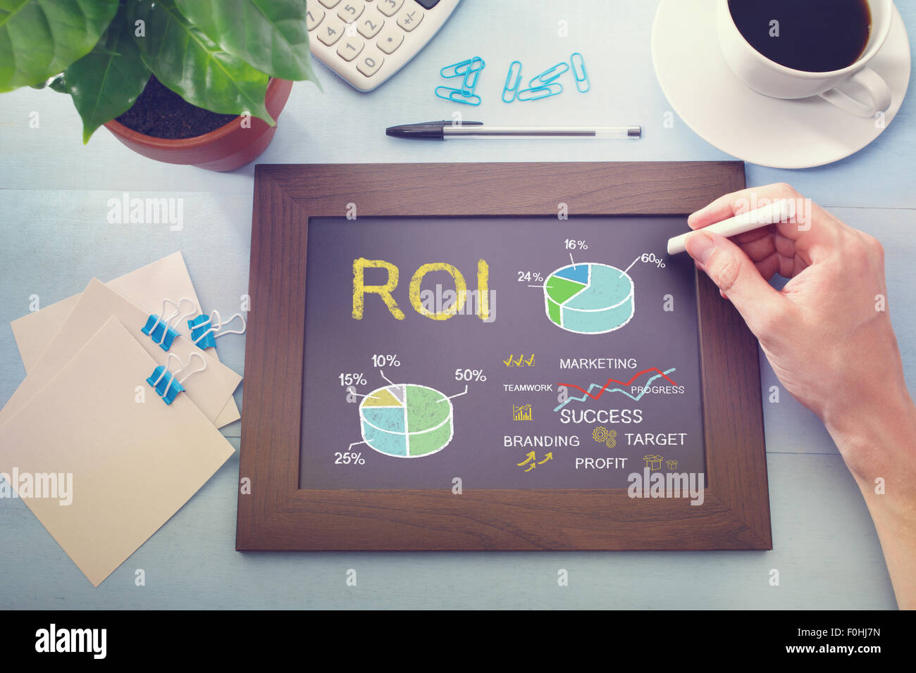 Man drawing ROI concept on chalkboard (return on investment) Stock Photo