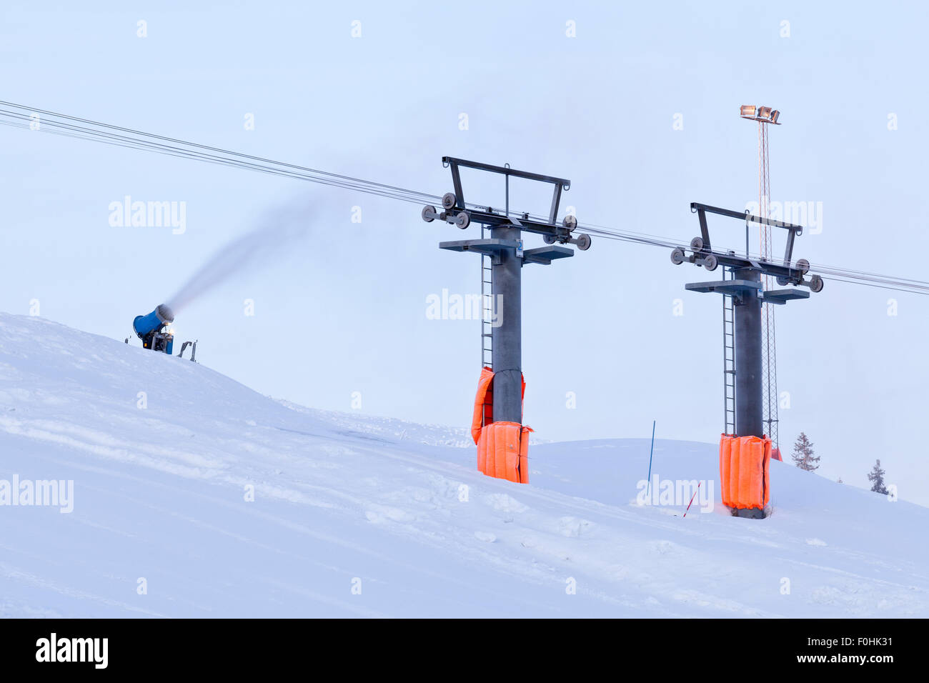 Downhill slope and snowmaking equipment in action. Ski lift and