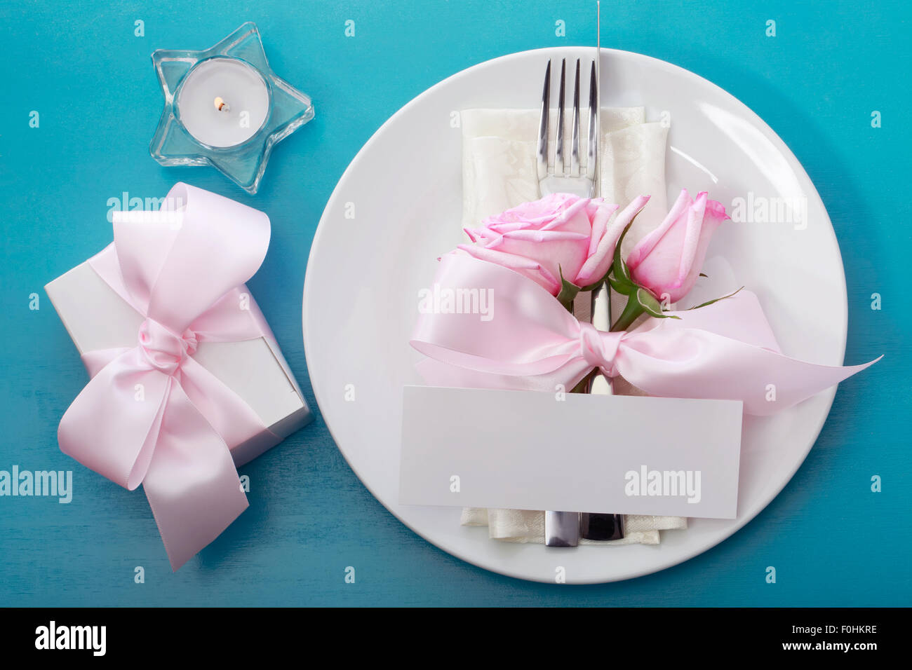 Table setting and gift box with pink roses Stock Photo