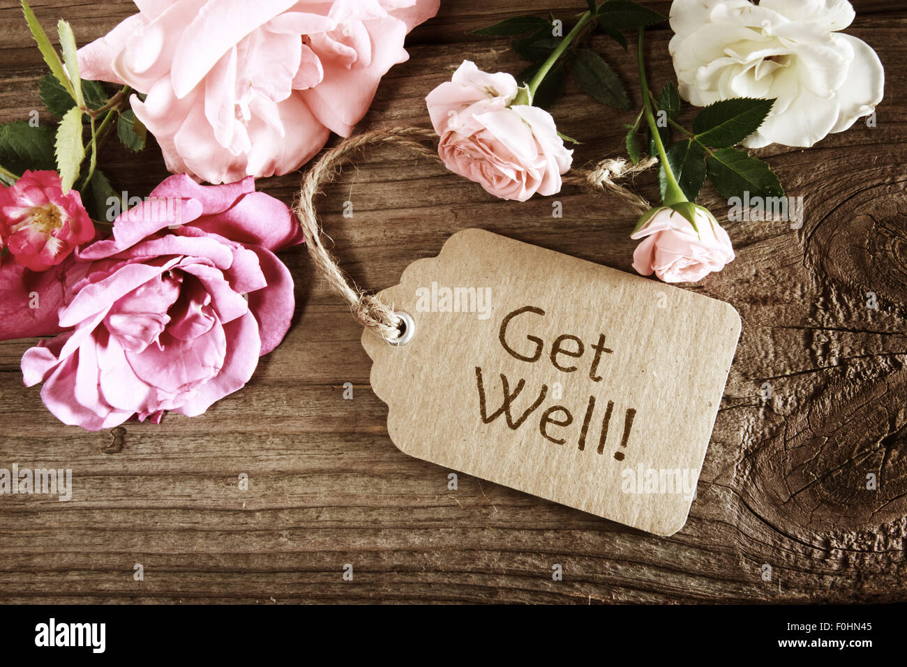 Get well message tag with roses wooden table Stock Photo