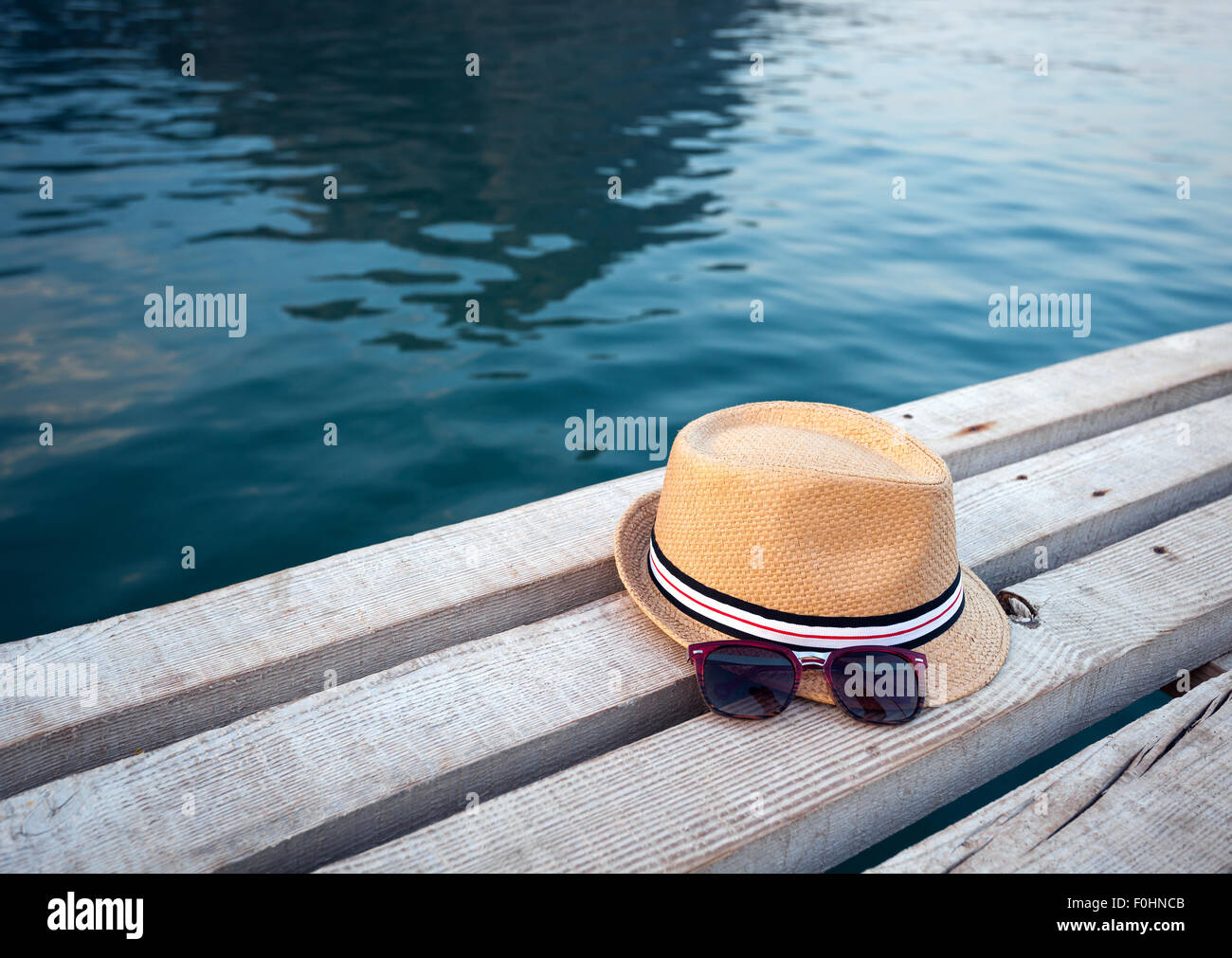 Sunglasses, flip-flops and hat on the wooden texture in summer. Stock Photo