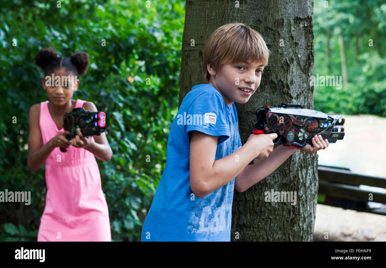 toy laser guns outdoor, boy and girl playing war game Stock Photo