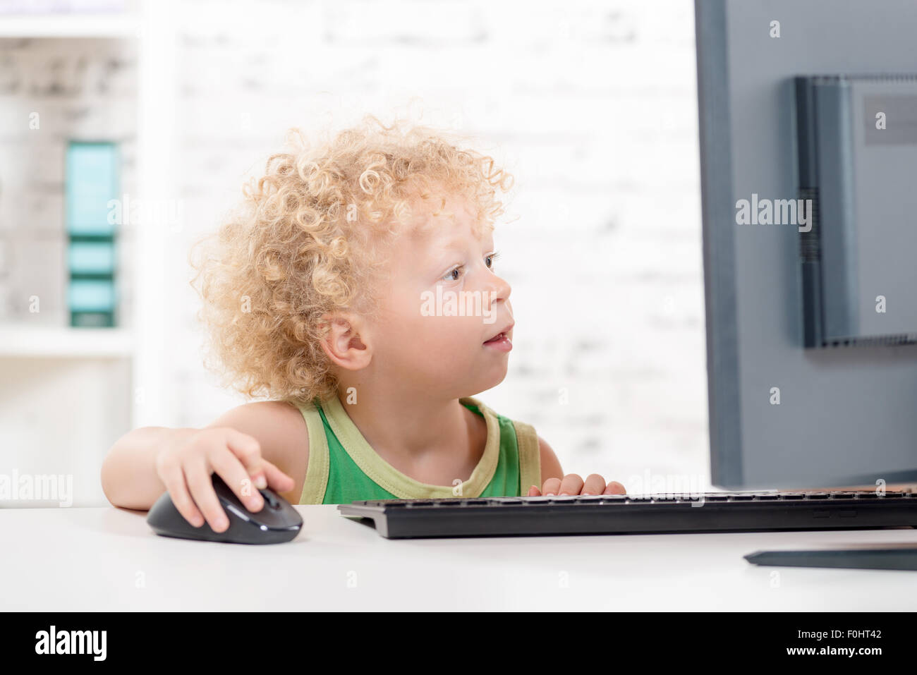 a little blond boy playing with the mouse of a computer Stock Photo - Alamy