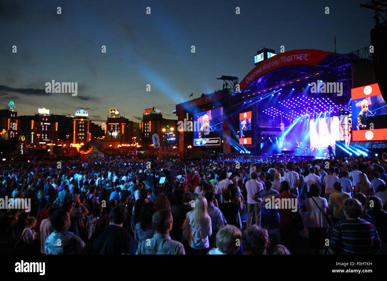 KYIV, UKRAINE - JUNE 30, 2012: People look on Sir Elton John performs onstage during charity Anti-AIDS concert at the Independence Square on June 30, 2012 in Kyiv, Ukraine Stock Photo