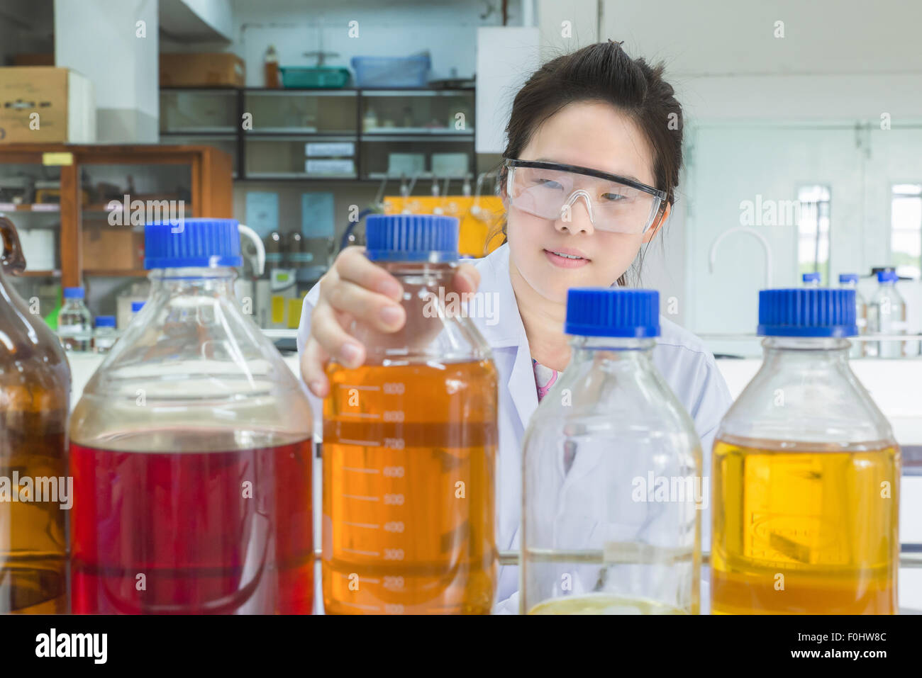 Asian scientist selecting bottle in shelf at laboratory Stock Photo
