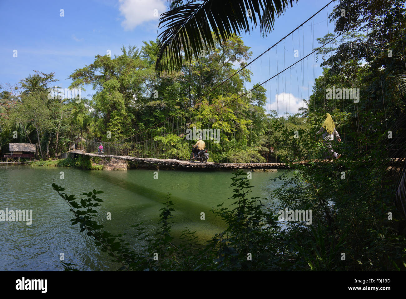 People cross what is know as the bamboo bridge, a suspension bridge made of bamboo, in Batukaras, West Java on 09 August 2015. Stock Photo
