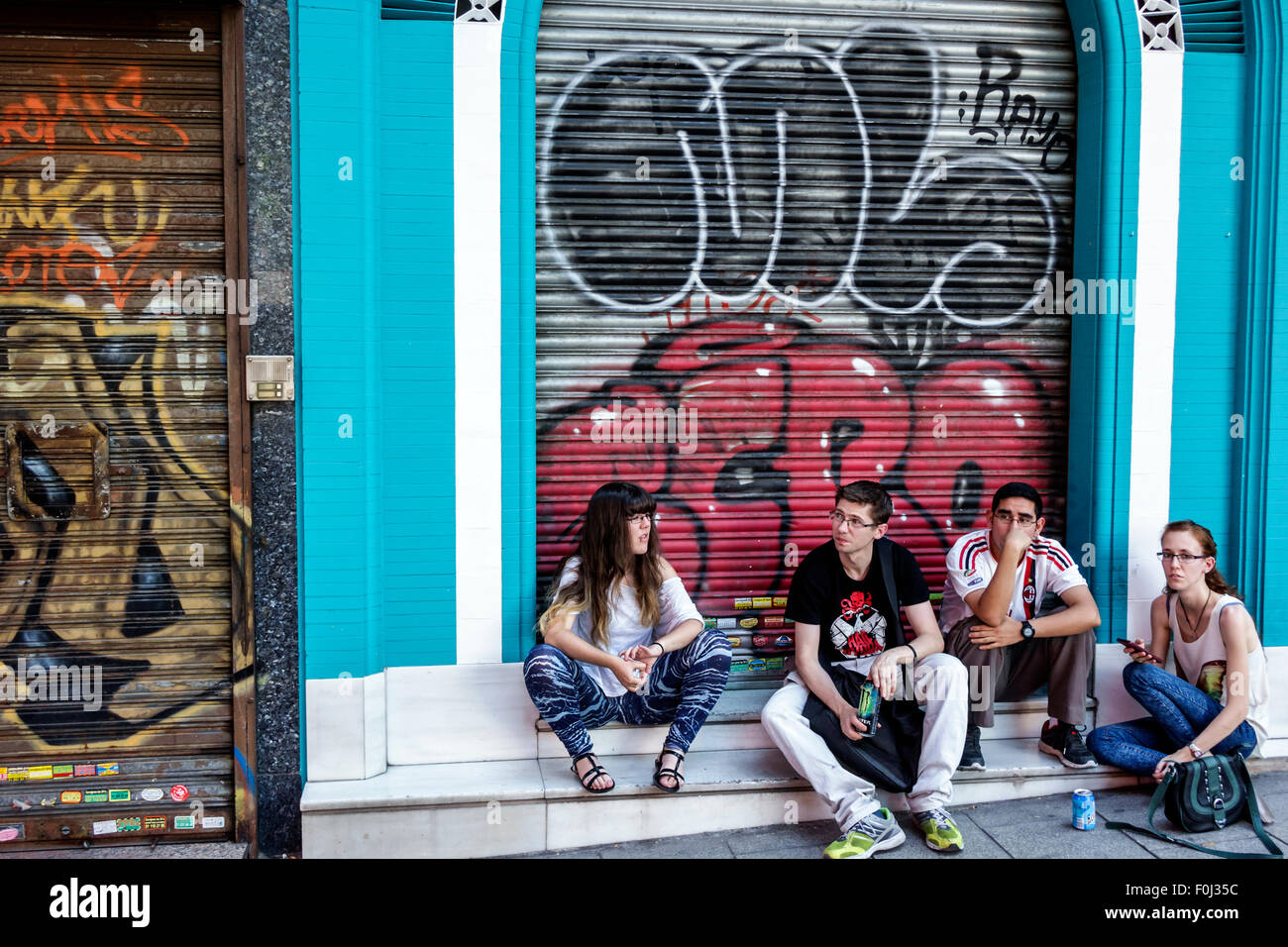 Madrid Spain,Hispanic Centro,Lavapias,Calle Argumosa,young adults,man men male,woman female women,couple,sitting,graffiti,Spain150628170 Stock Photo