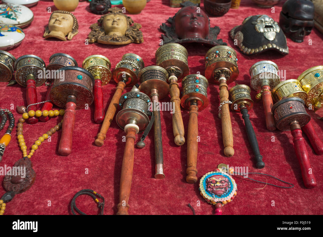Buddhist prayer wheels for sale laying down on a red table in a market, Tibet, China 2013. Stock Photo
