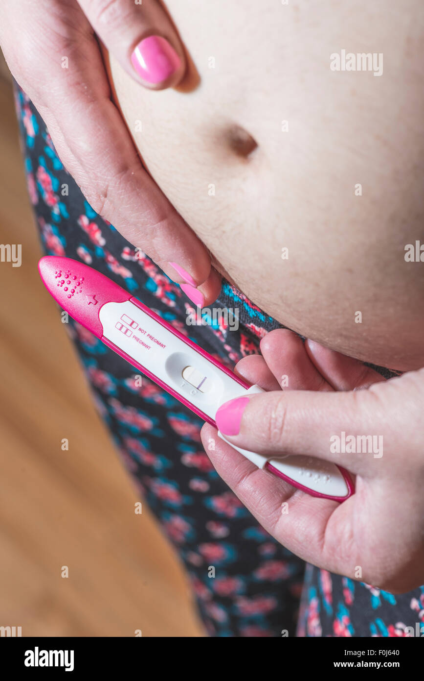 Pregnant woman holding a pregnancy test. Close up Stock Photo