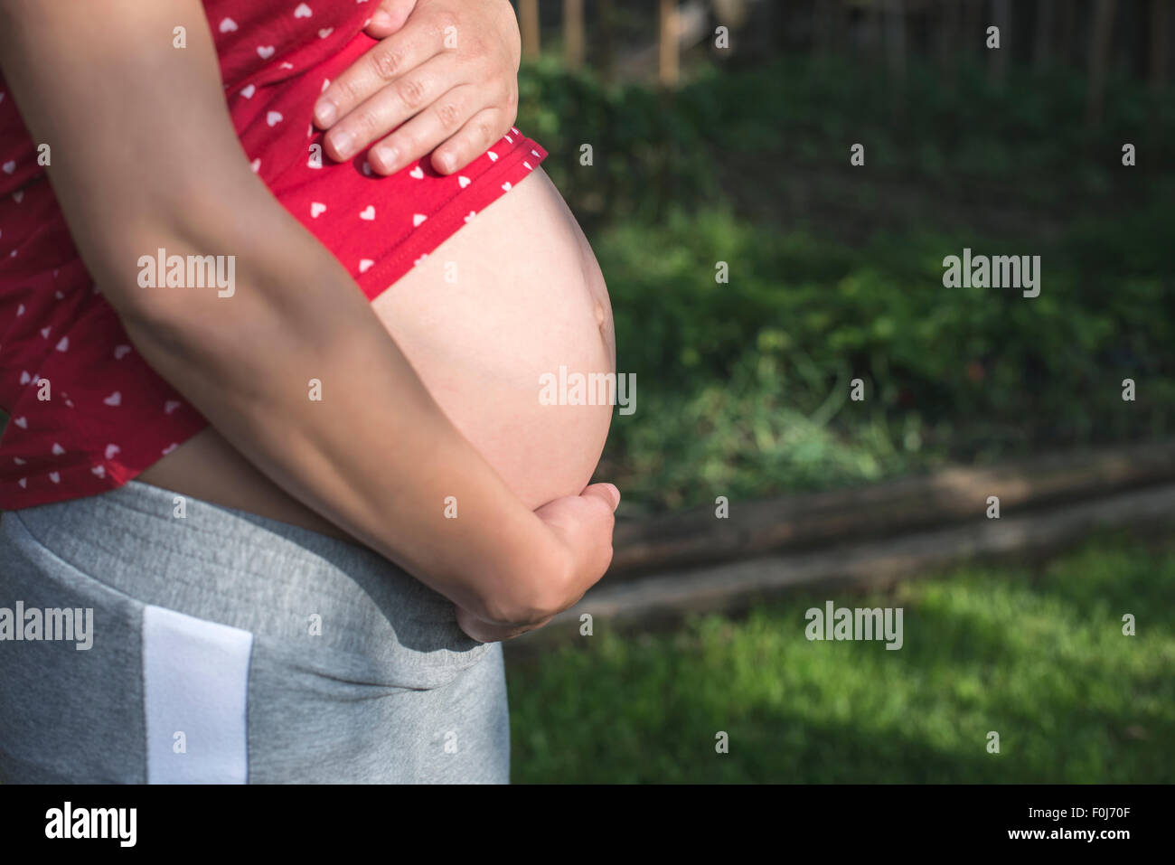 Pregnant woman shows his belly. In the nature. Green meadow Stock Photo