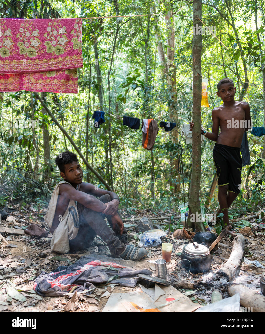 Two young men of the Orang Asil tribe sitting on the ground in the jungle and making tea, native, indigenous people Stock Photo