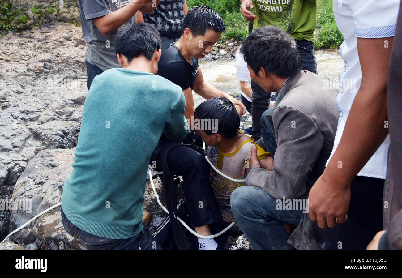 Weining, China's Guizhou Province. 16th Aug, 2015. People rescue a boy at Diaoshui Village of Mazha Town in Weining County, southwest China's Guizhou Province, Aug. 16, 2015. The boy was washed down the waterfall and hung between the cliffs on Sunday. © Yang Wenbin/Xinhua/Alamy Live News Stock Photo