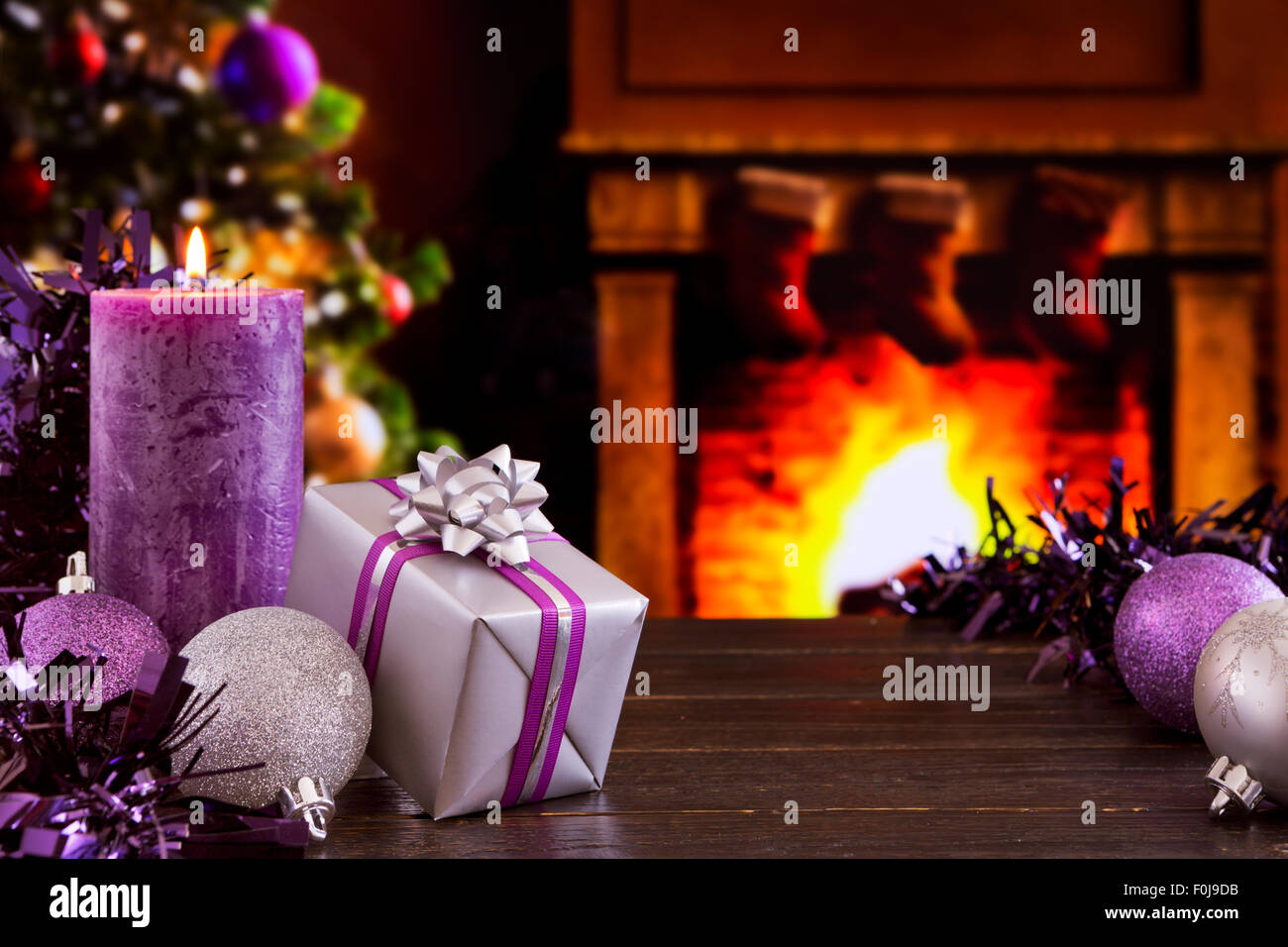 Christmas decorations, a gift and candles in front of a fireplace. A