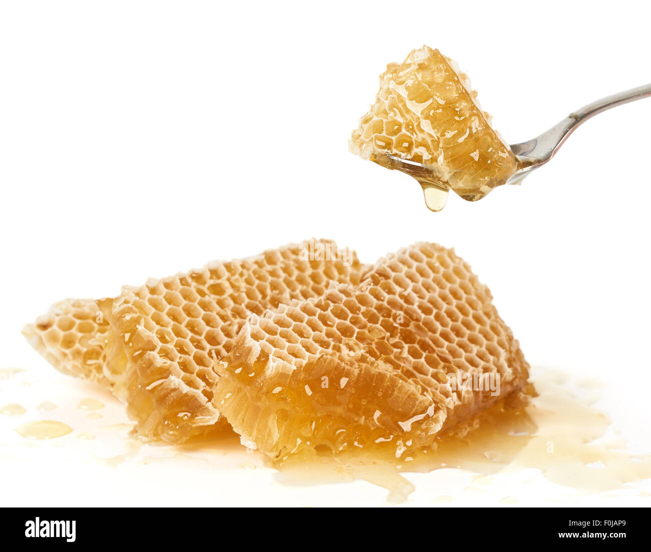 Spoon of raw honey over pieces of honey comb Stock Photo - Alamy