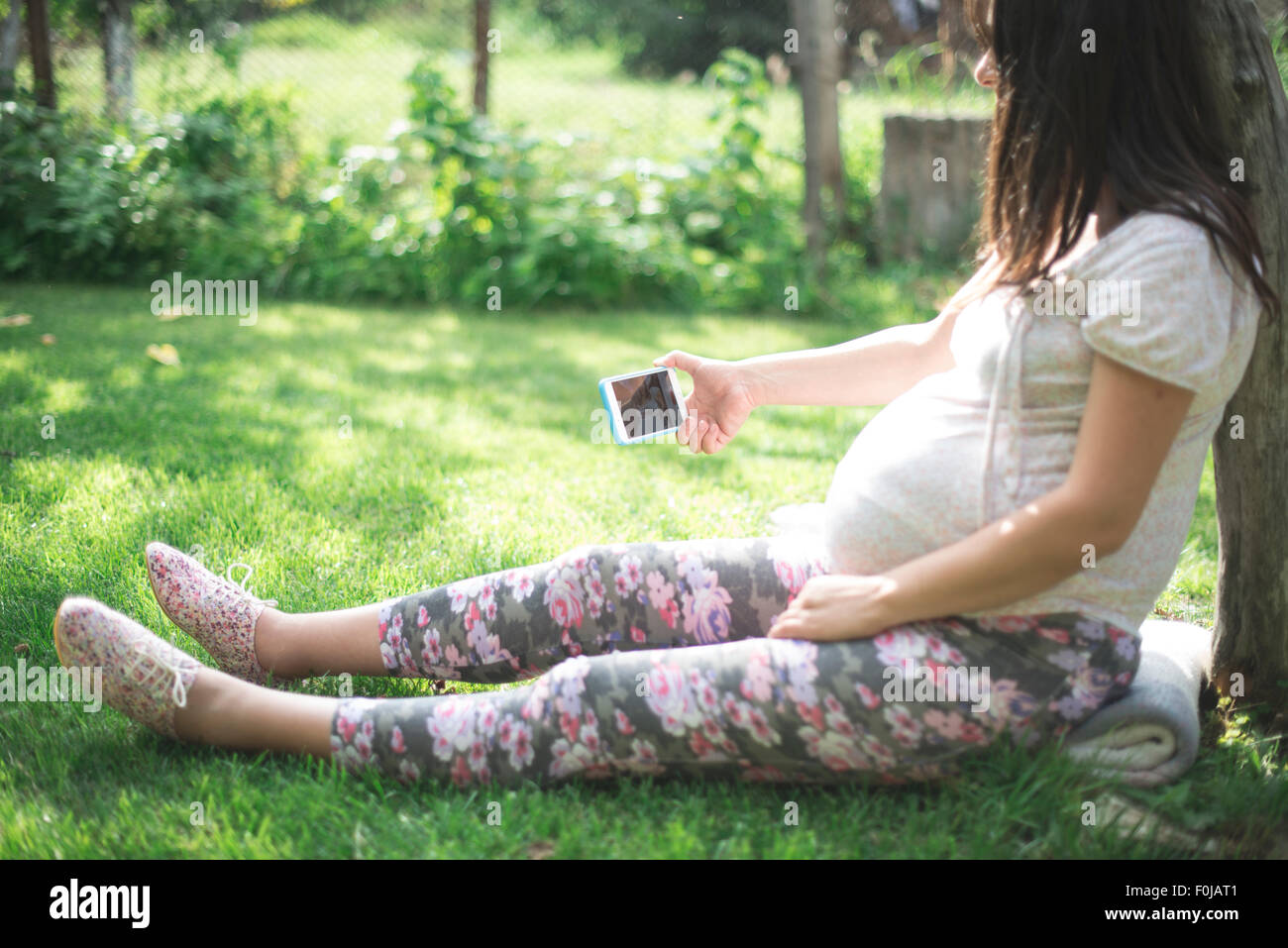 Pregnant women with smartphone in a garden Stock Photo