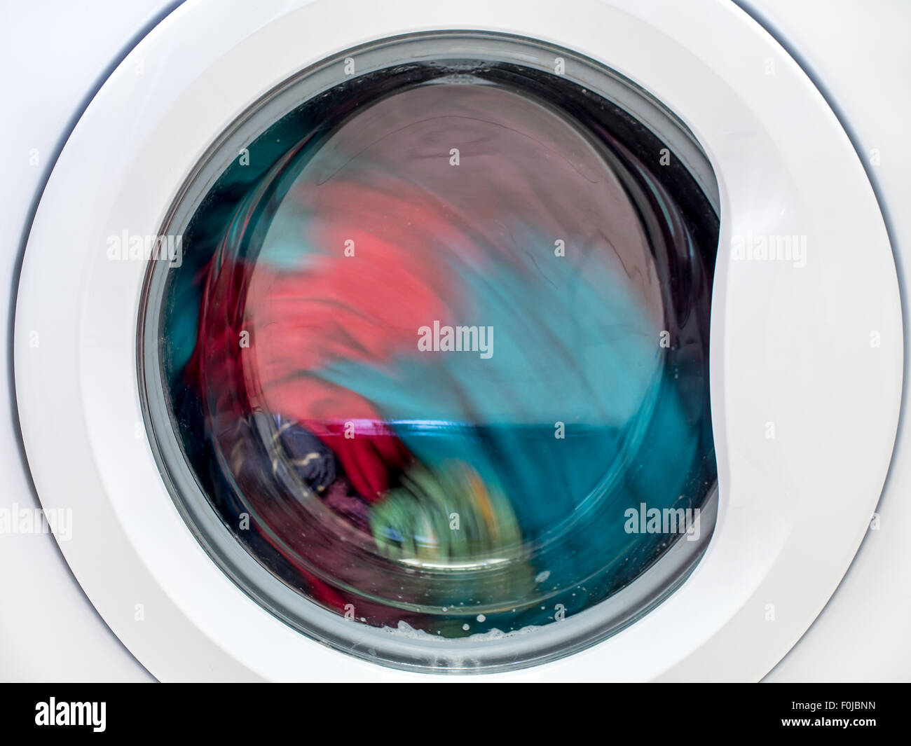 Closeup of washing machine door with spinning laundry Stock Photo