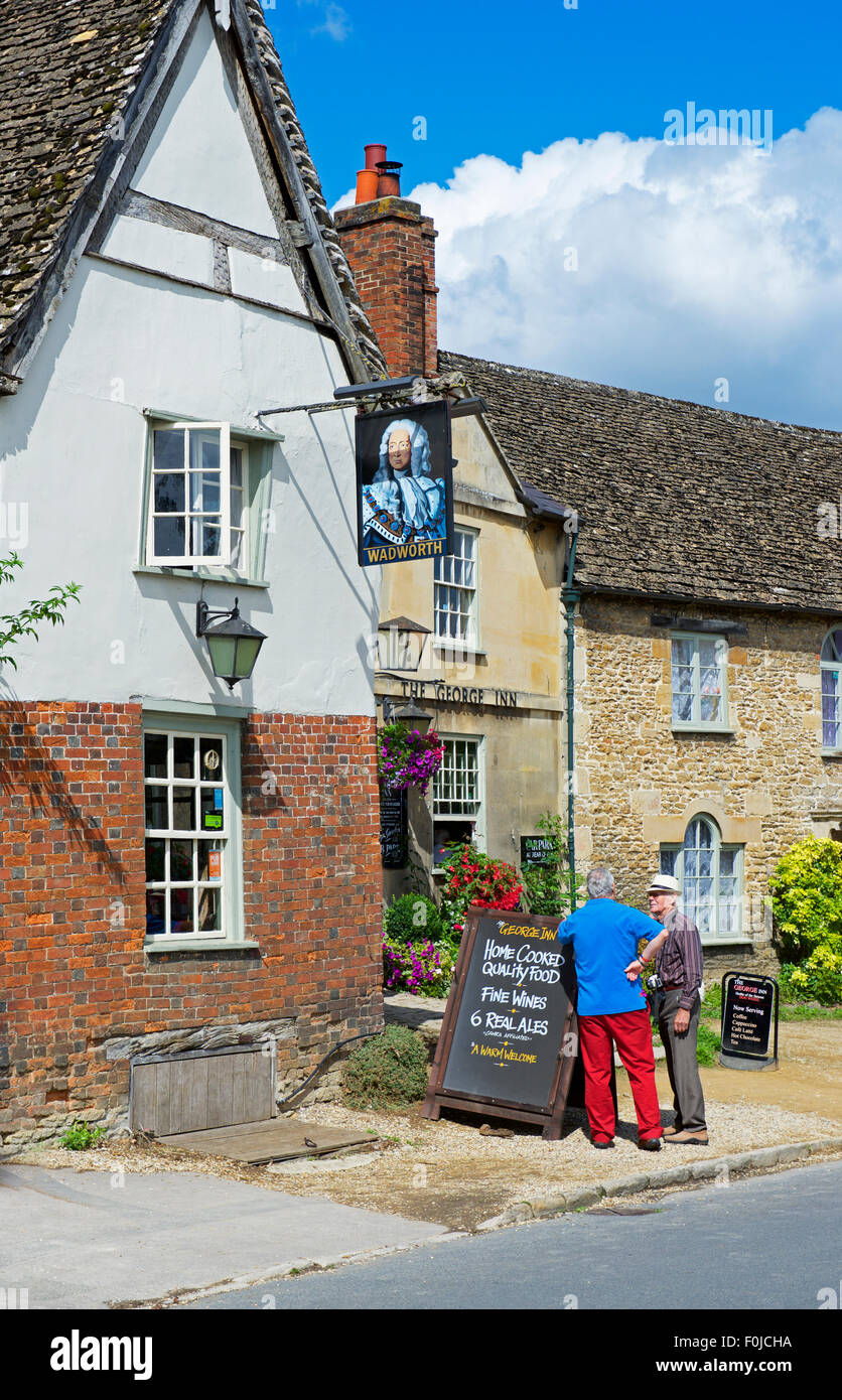 Two senior men standing outside the George Inn, Lacock, Wiltshire, England UK Stock Photo