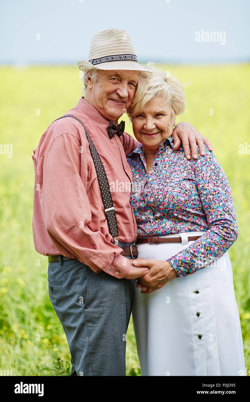 Romantic seniors in embrace looking at camera outdoors Stock Photo