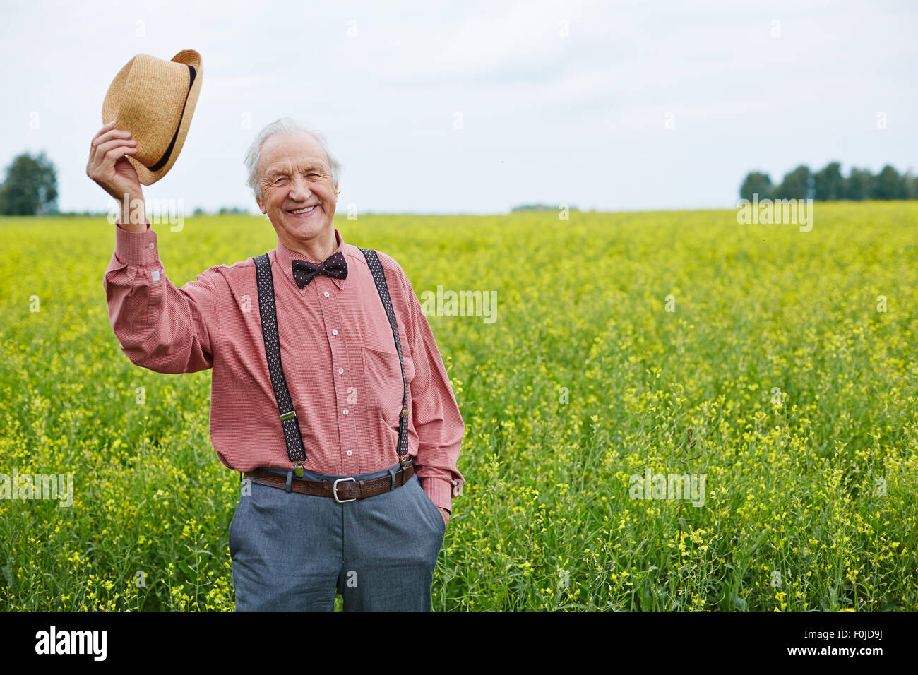 Cheerful senior man in smart casual looking at camera with his hat in hand Stock Photo