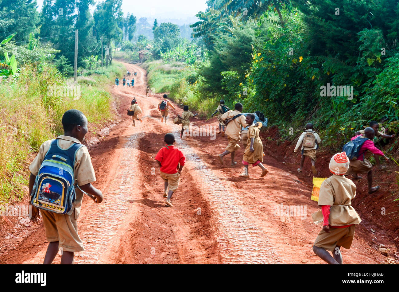 Kids running after school on a red earth dirt road in rural Africa Stock Photo