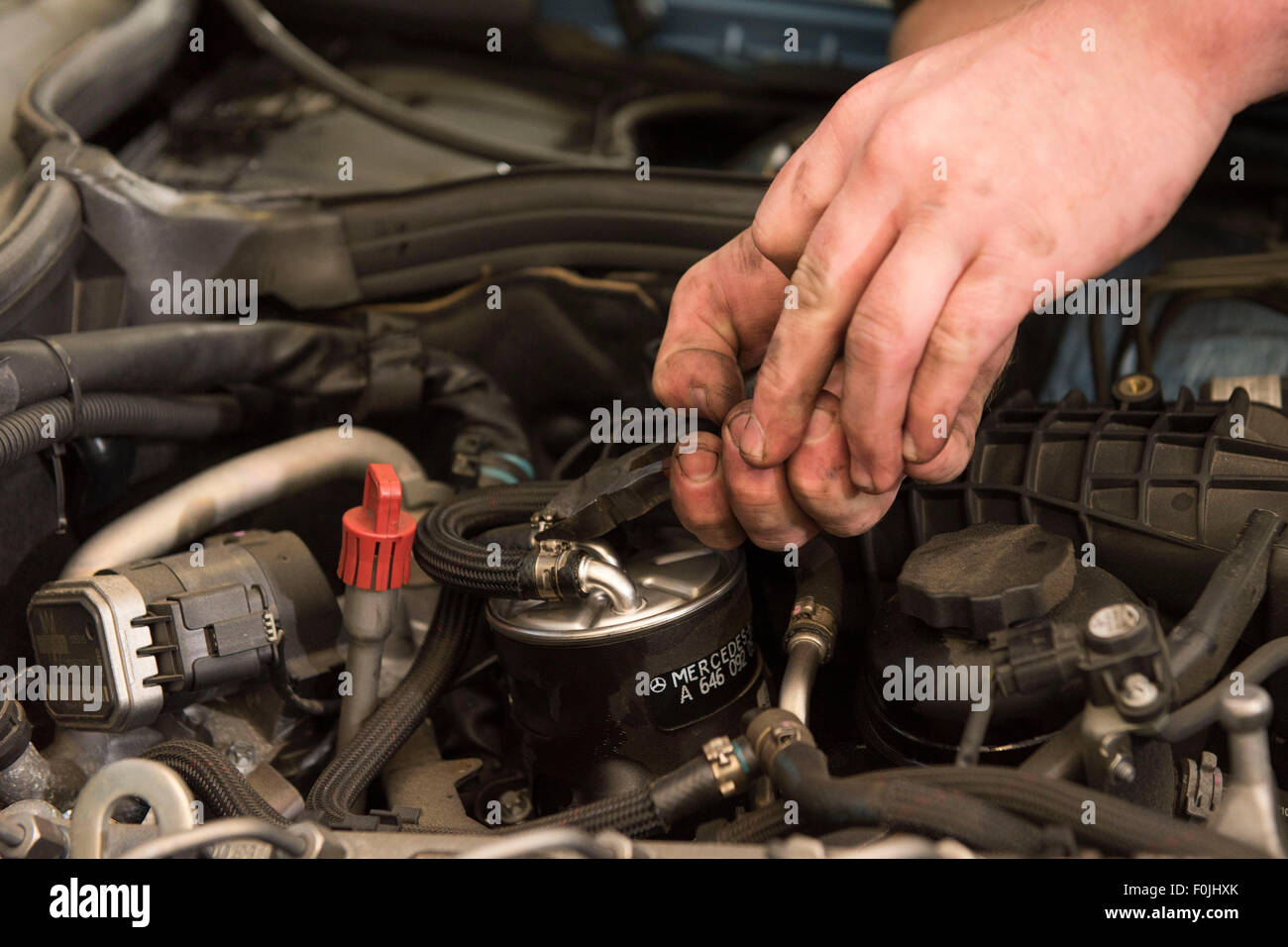 A car mechanic performing routine maintenance replacing an oil filter on a car in a car garage during an MOT. Stock Photo