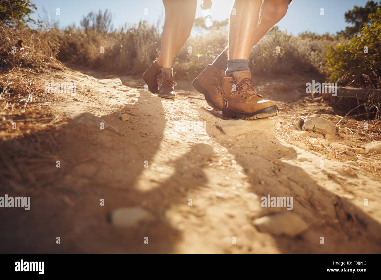 Hiking shoes in action on a country trail path. Closeup of male hikers