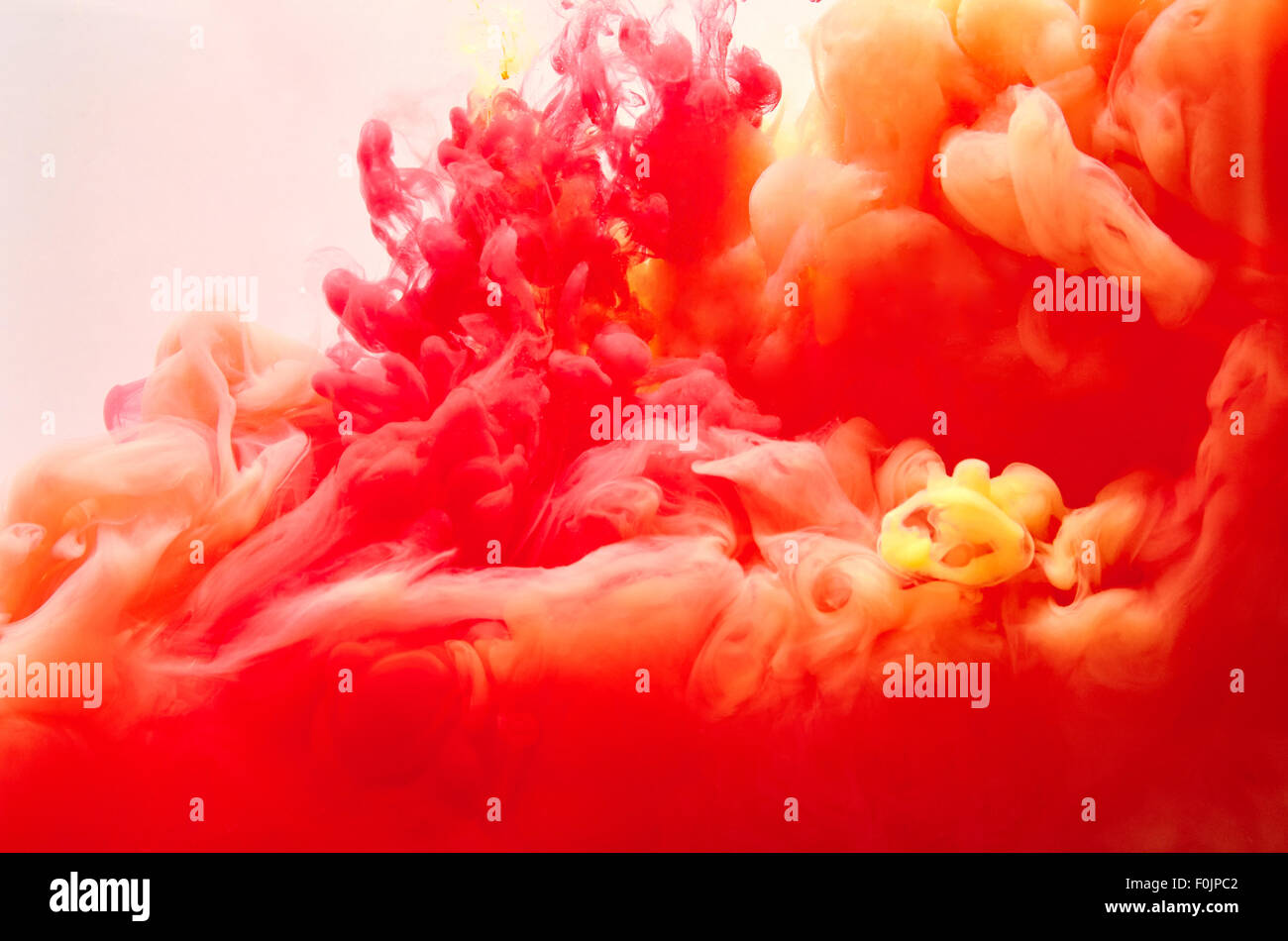 Red and yellow inks making clouds in water Stock Photo