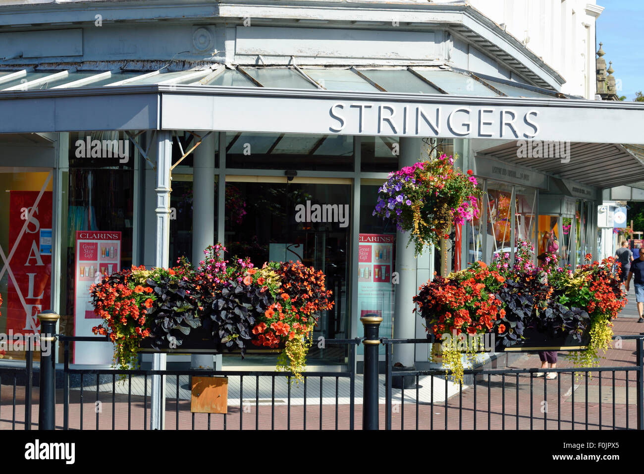 Row of colourful hanging baskets and window boxes outside a shop in Lytham, Lancashire Stock Photo