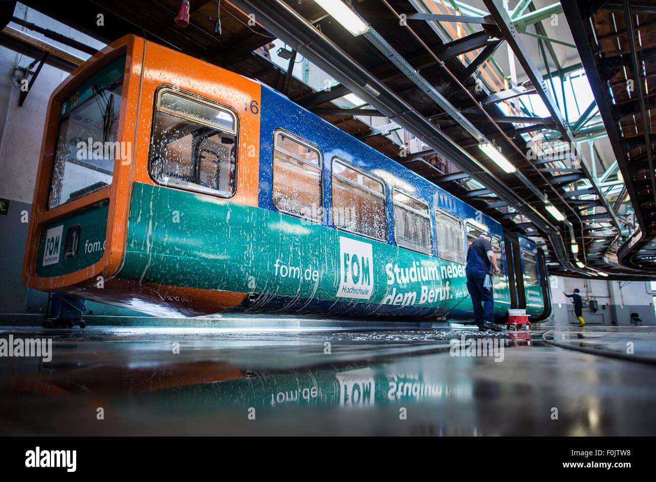 Wuppertal, Germany. 13th Aug, 2015. A man cleans a carriage in the workshop of the suspension railway located at its terminal station in Wuppertal, Germany, 13 August 2015. Wuppertal's public utility company WSW will give away three carriages of its well-known railway for free, with an additional 21 from the 1970s to be sold for 5,000 euros next year when the fourth generation of the railway is scheduled to commence operations. Photo: Maja Hitij/dpa/Alamy Live News Stock Photo