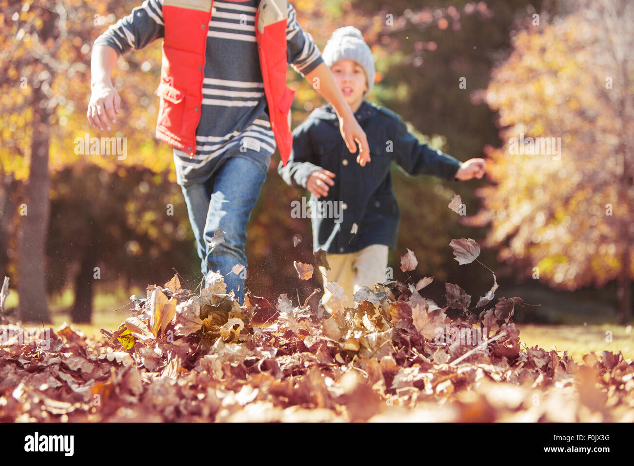 Boys running in autumn leaves Stock Photo - Alamy