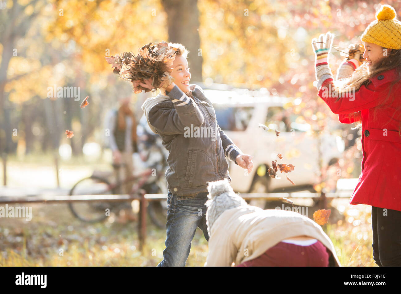 Boy throwing autumn leaves at girl in park Stock Photo
