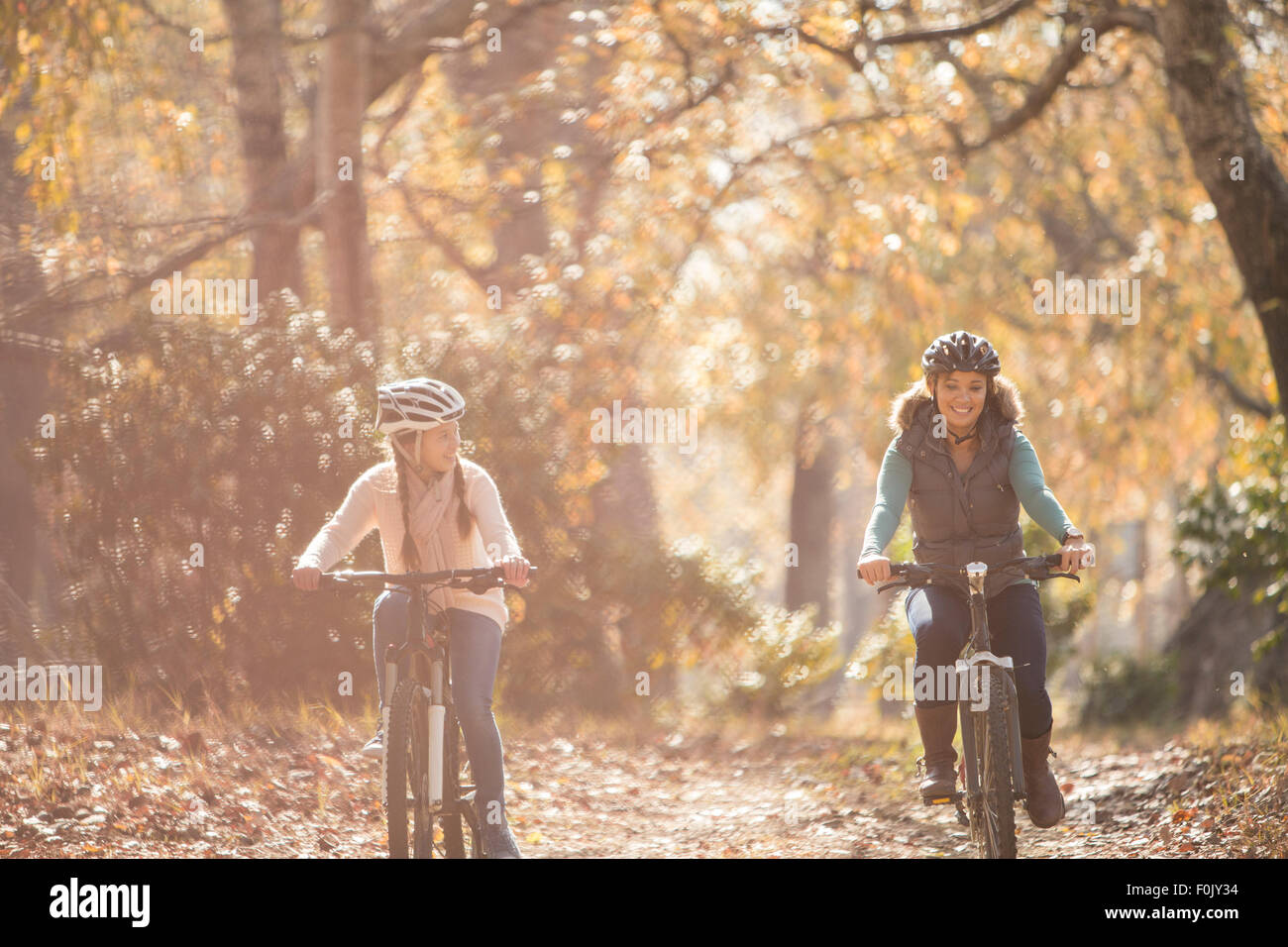 Mother and daughter bike riding on path in woods Stock Photo