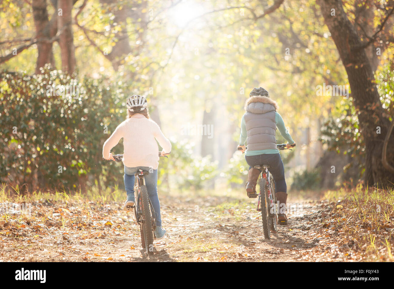 Mother and daughter bike riding on path in woods Stock Photo