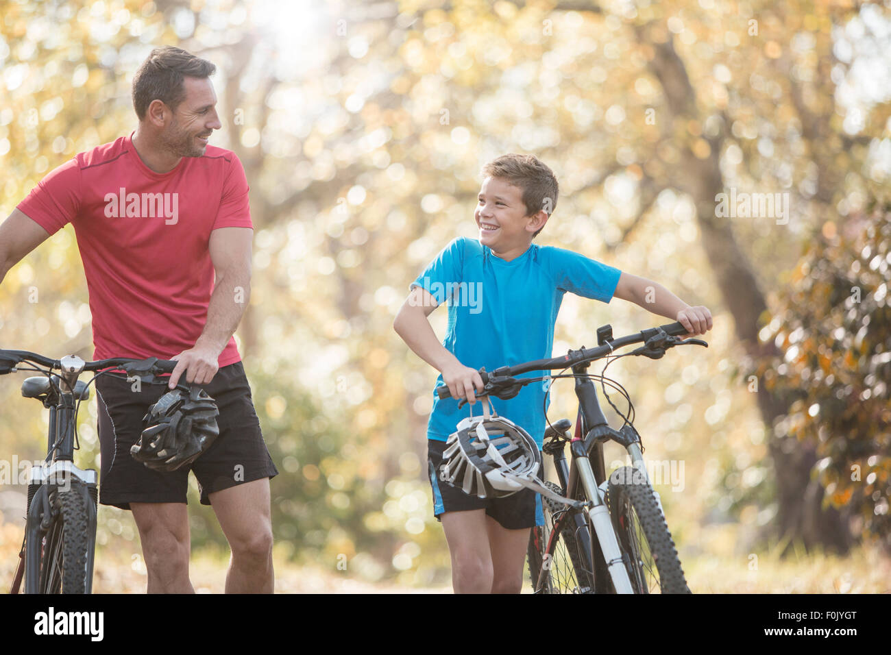 Father and son walking mountain bikes in woods Stock Photo