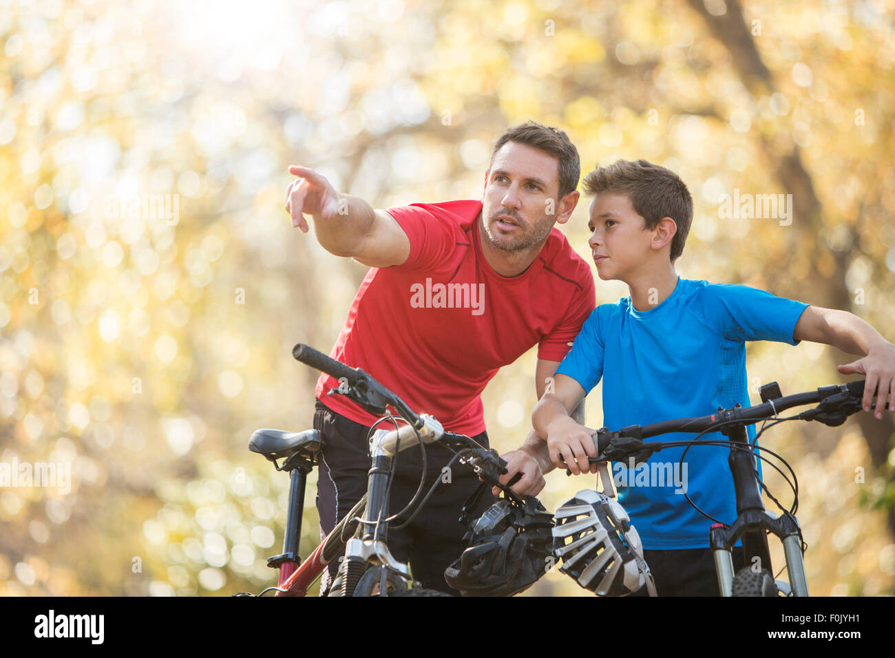Father pointing and explaining to son on mountain bikes Stock Photo