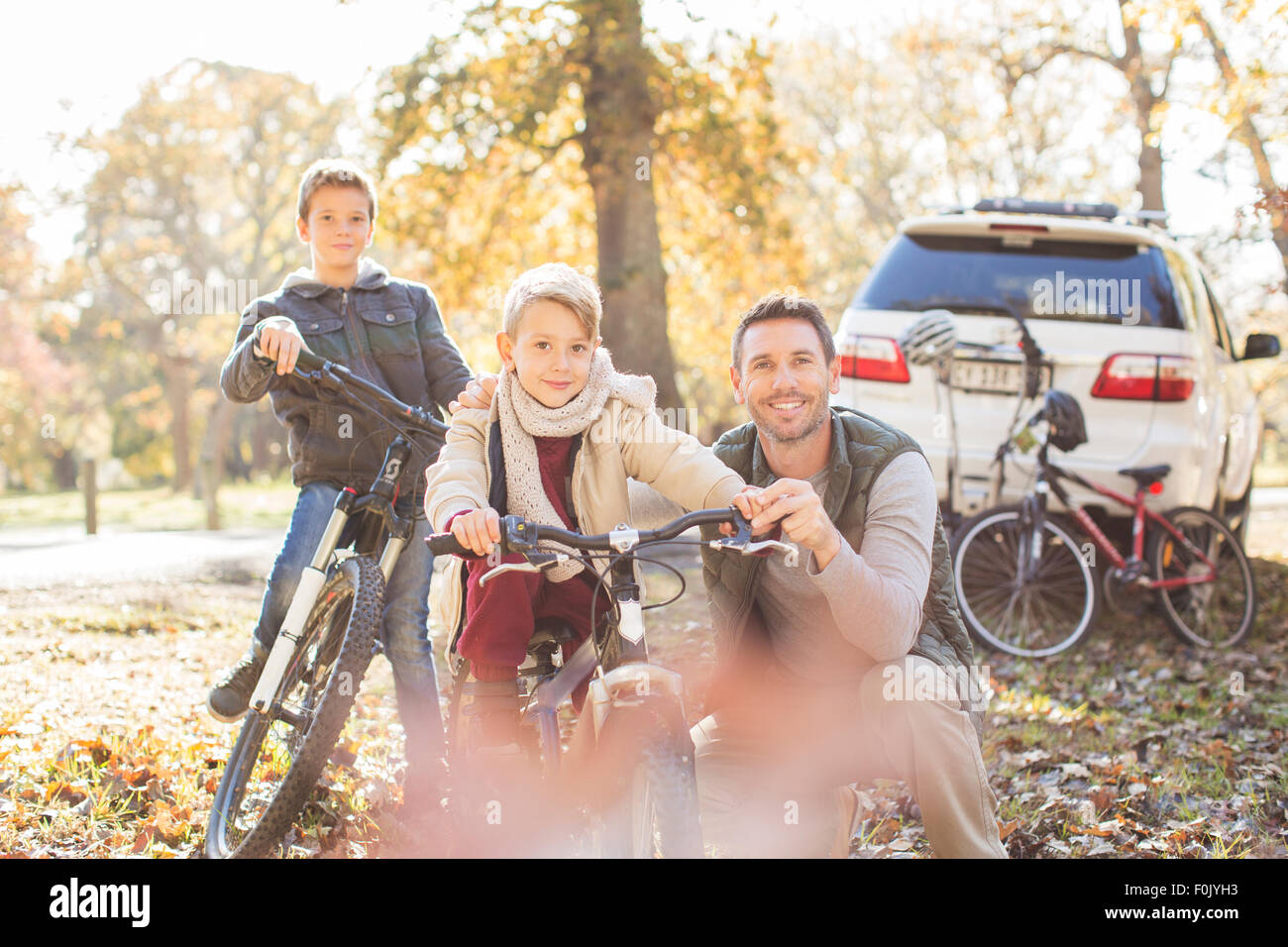 Portrait father and sons with bicycles in autumn park Stock Photo - Alamy