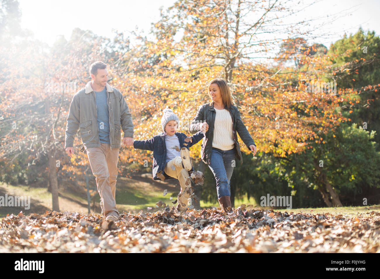 Family holding hands and walking in autumn leaves Stock Photo