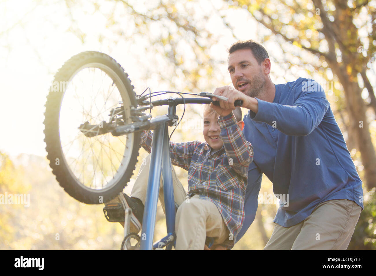 Father teaching son wheelie on bicycle Stock Photo