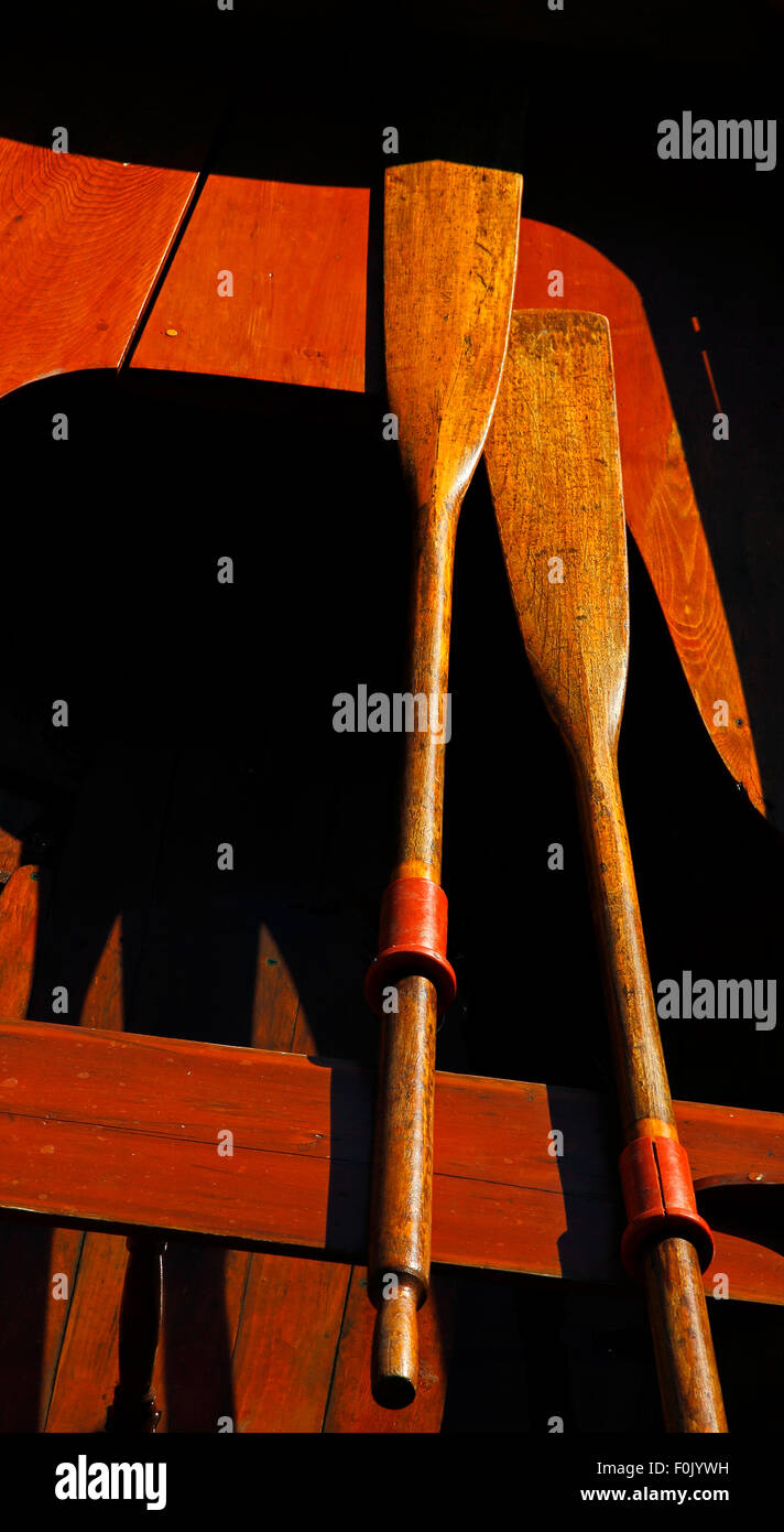 Vintage wooden boat in sun, harsh shadows, oars, seats. Stock Photo