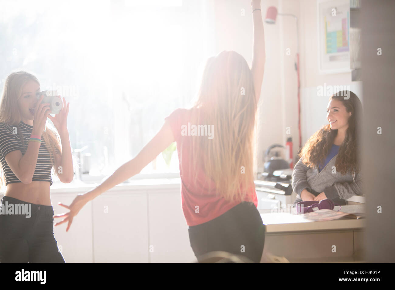 Teenage girls dancing and photographing in kitchen Stock Photo