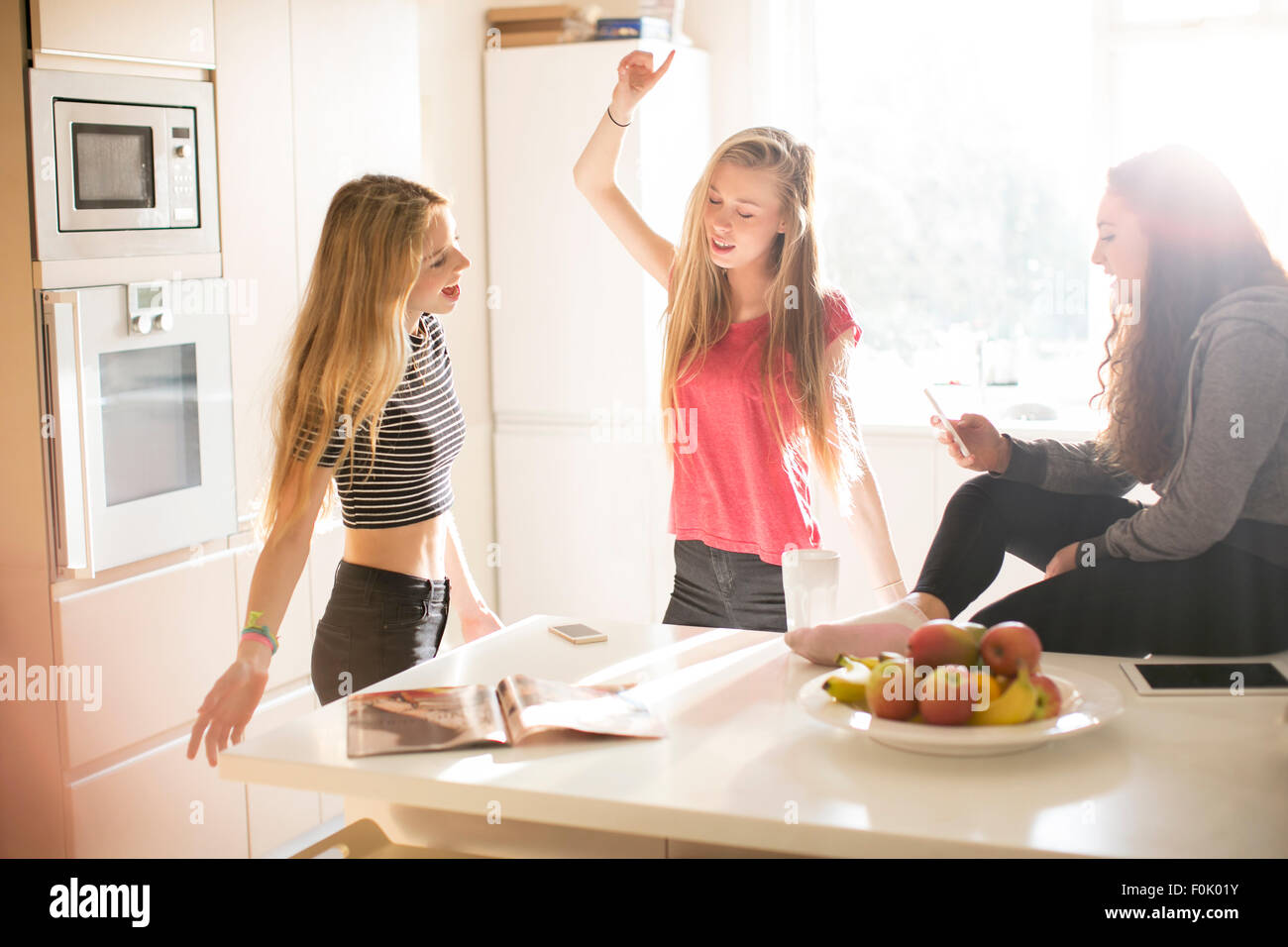 Teenage girls dancing in sunny kitchen Stock Photo Alamy