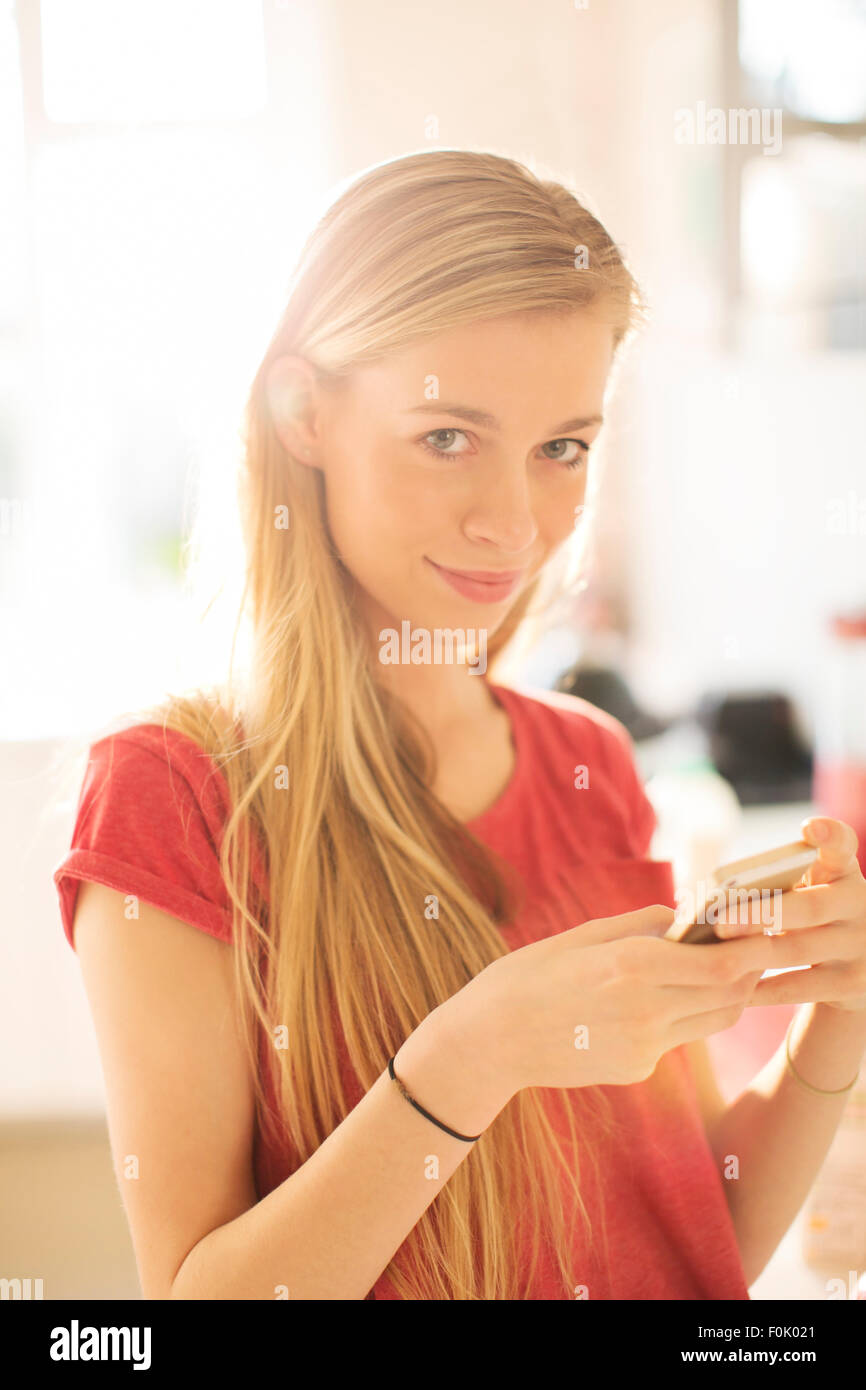 Portrait blonde teenage girl texting with cell phone Stock Photo