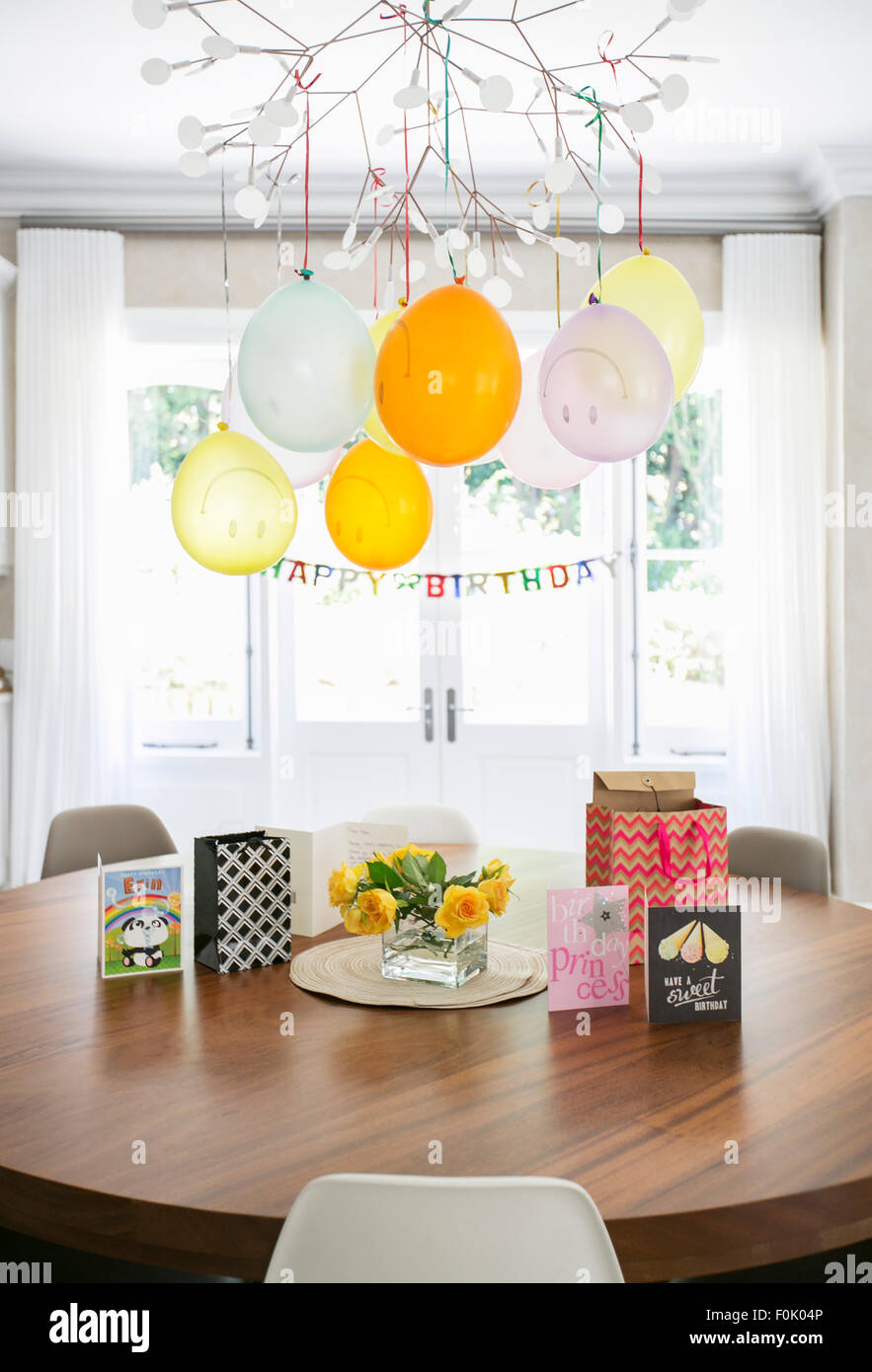 Smiley face balloons and Happy Birthday sign hanging over table with cards Stock Photo