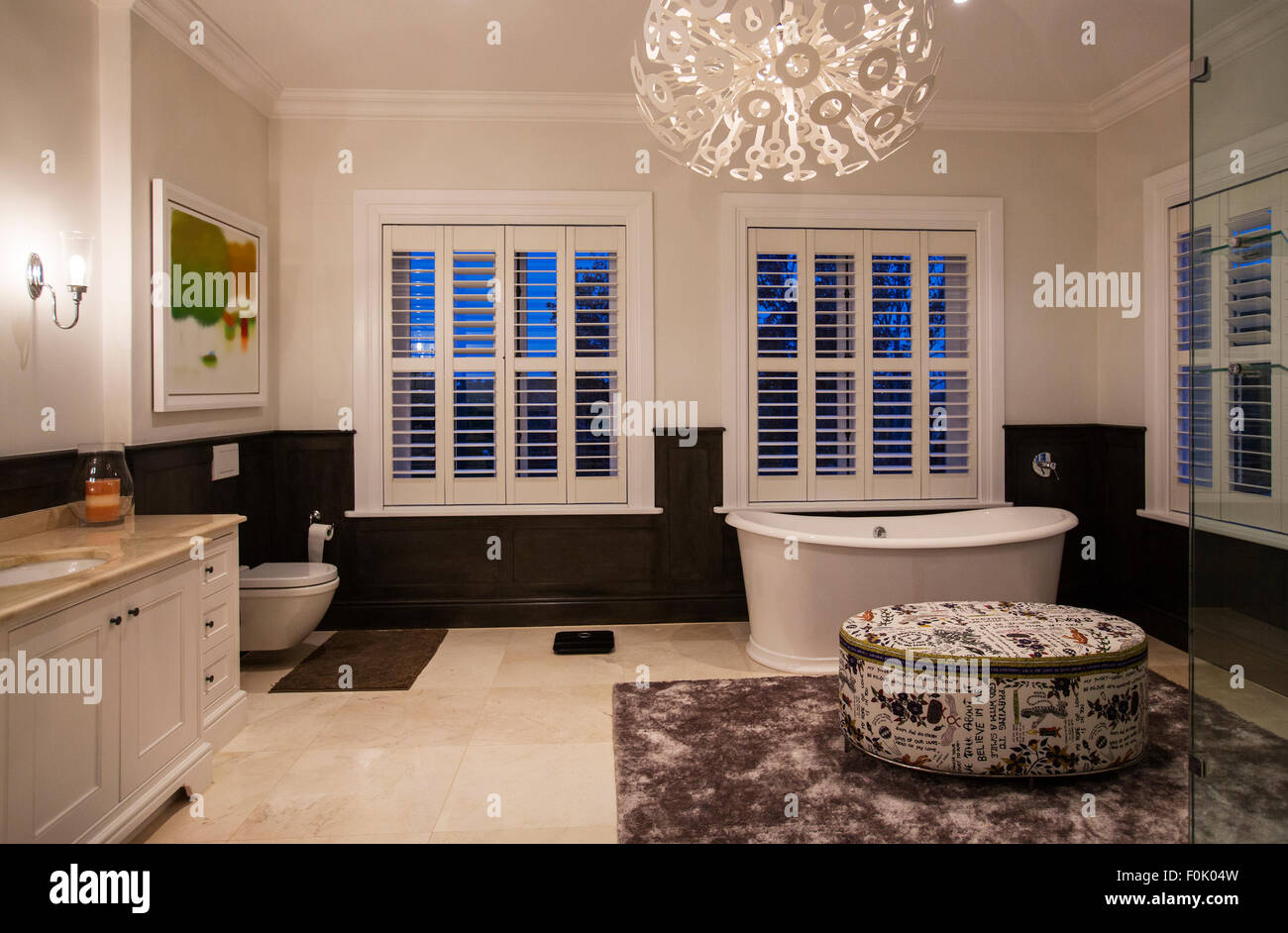 Soaking tub and modern chandelier in luxury bathroom at night Stock Photo
