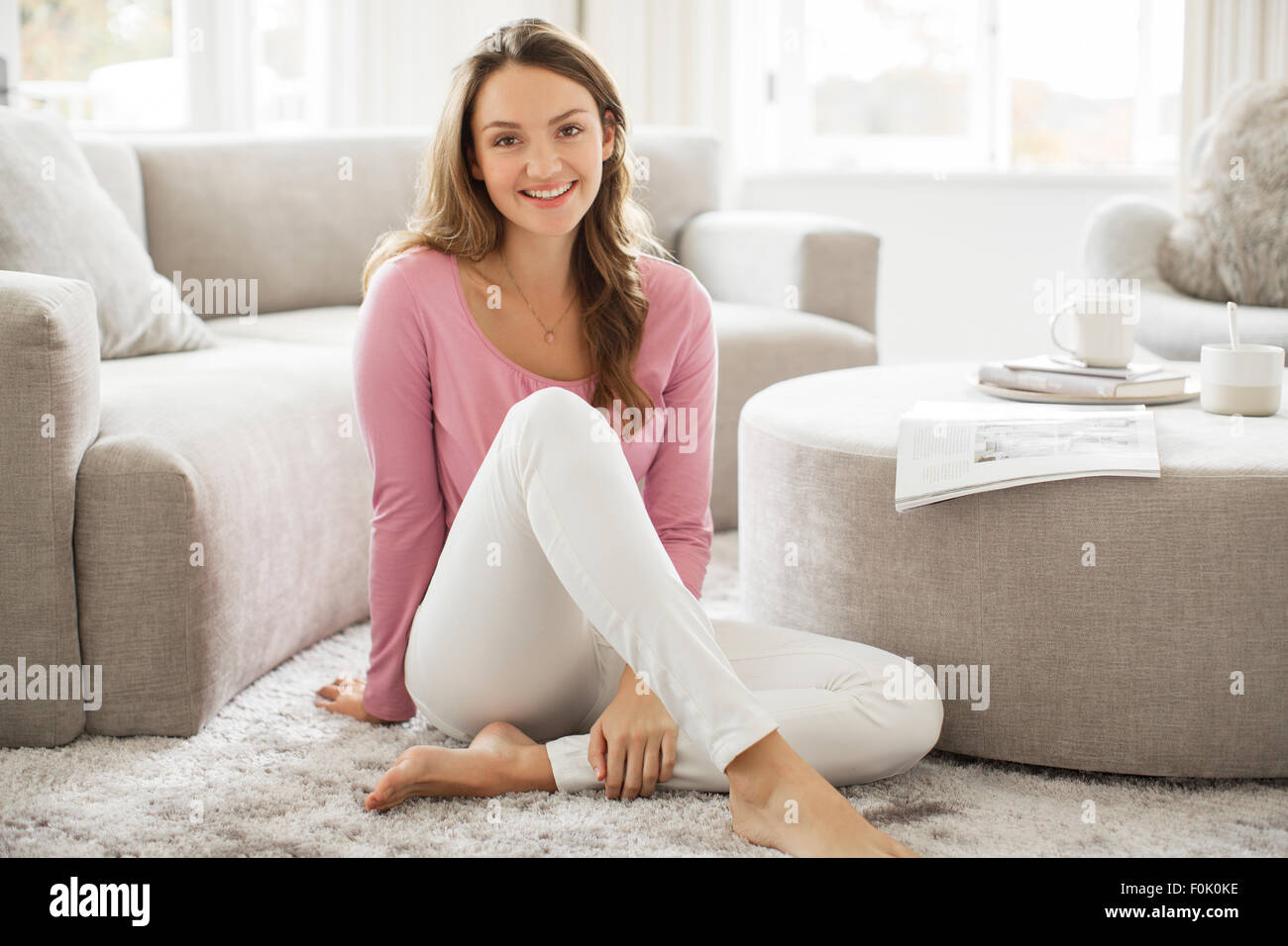 Portrait smiling barefoot woman in living room Stock Photo