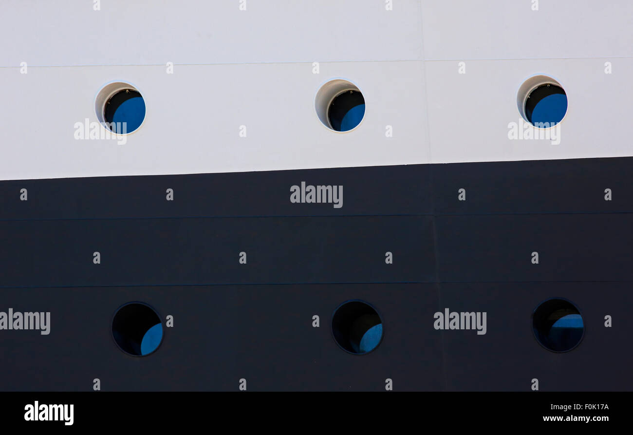 Six portholes on a multi-colored side of a cruise ship. Stock Photo