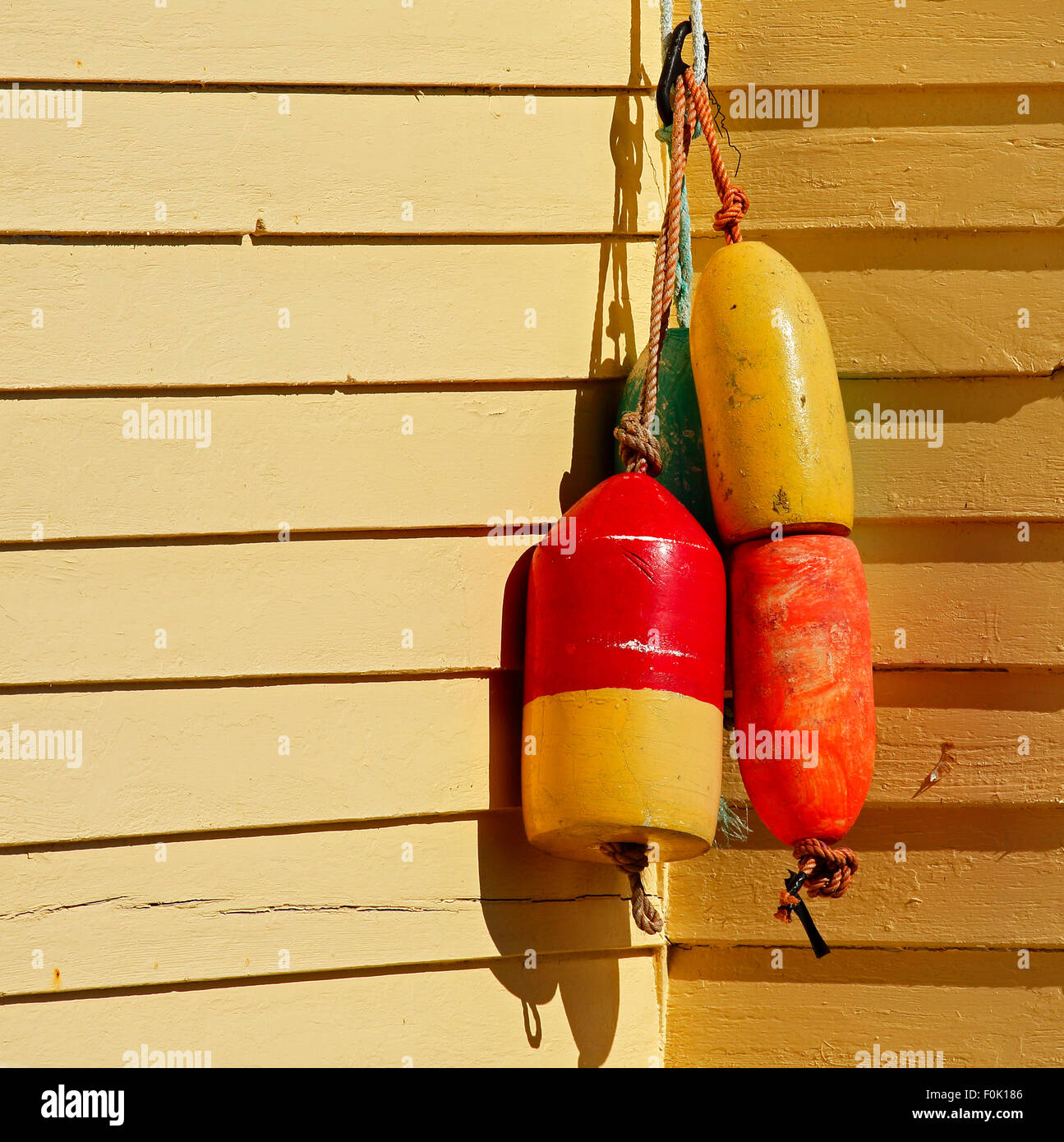 Fishing buoys hang on wood shingled wall. Stock Photo