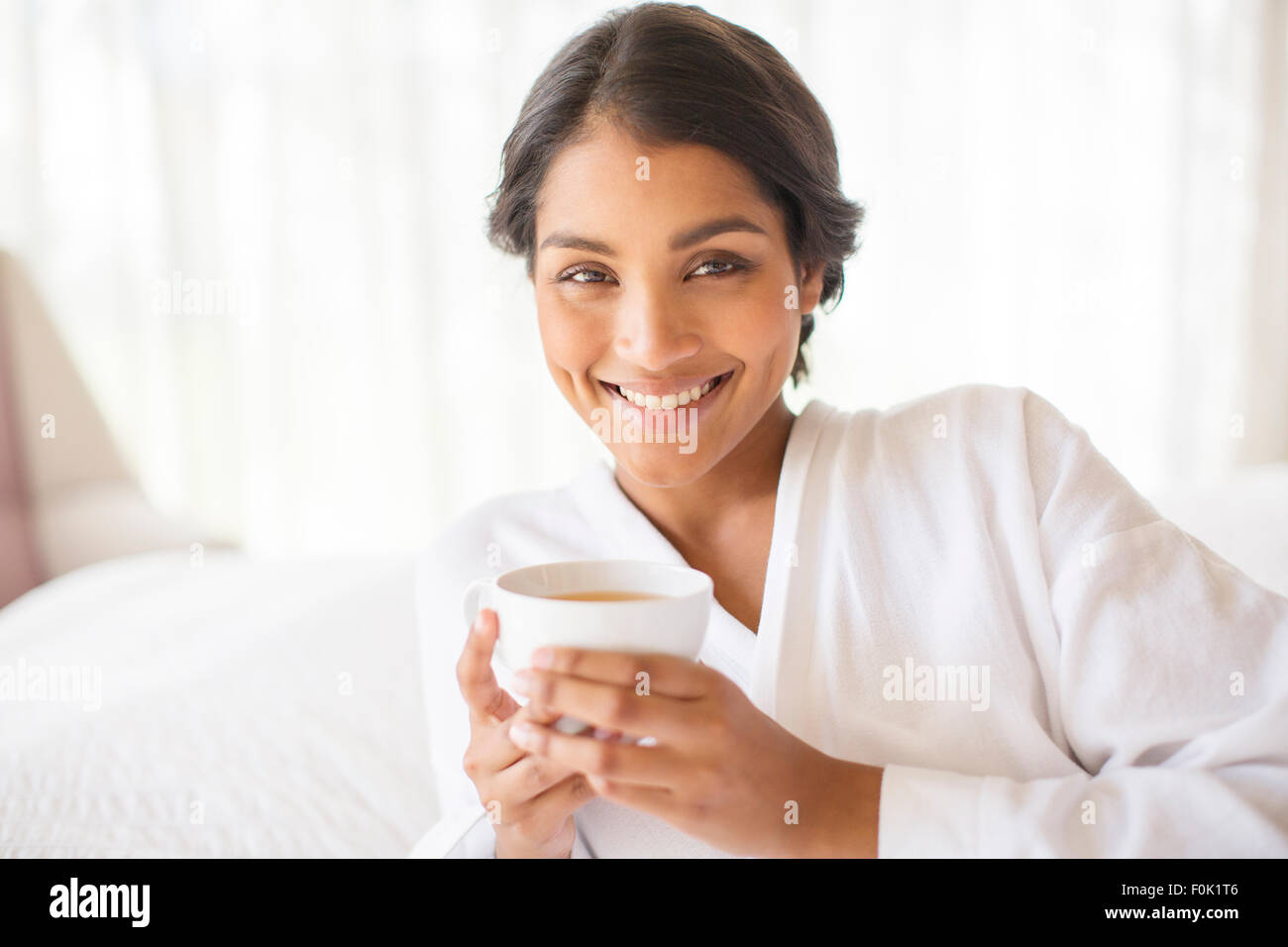 Portrait smiling woman in bathrobe drinking tea Stock Photo