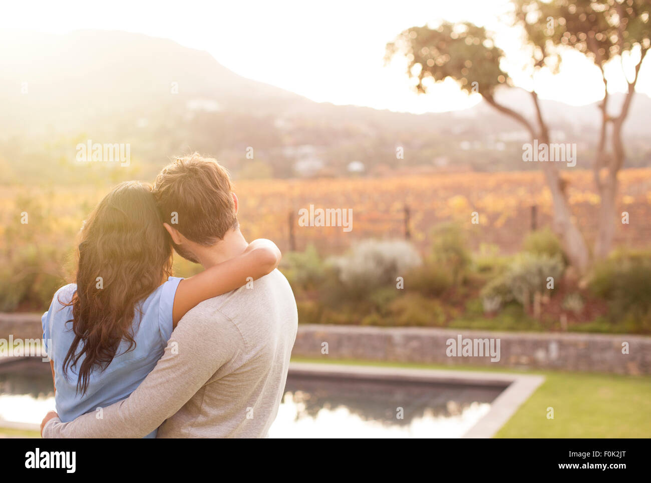 Couple hugging and looking at mountain view poolside Stock Photo