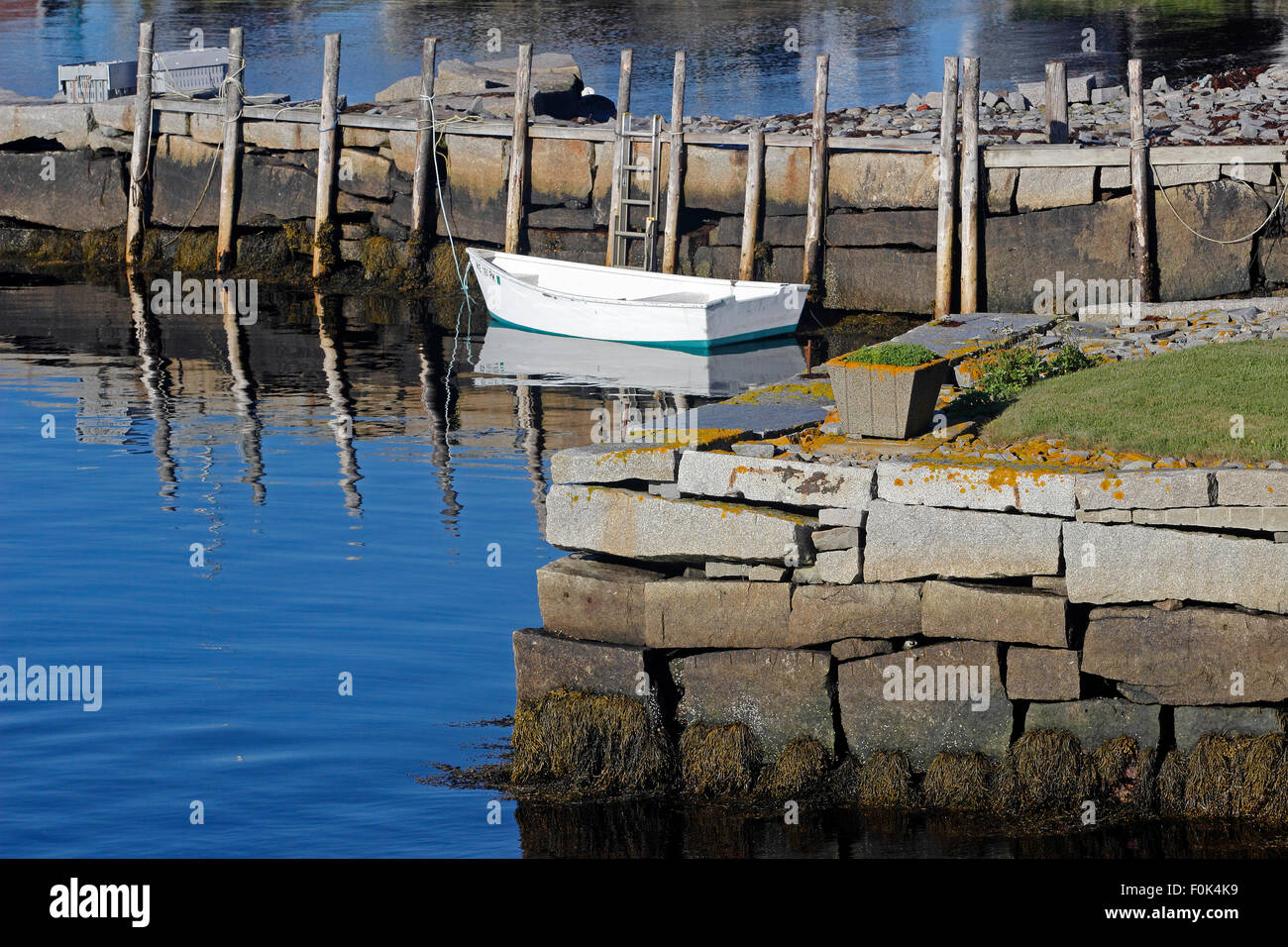 White dingy and granite wharfs in harbor Vinalhaven Island Maine New England USA Stock Photo